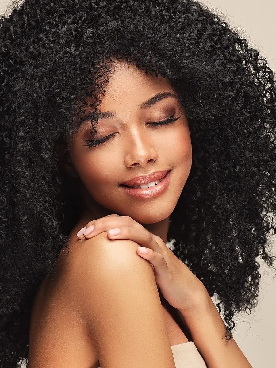 Woman with curly hair touching her shoulder